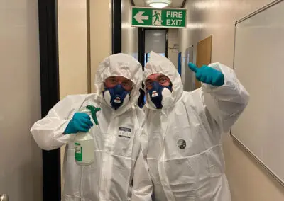 Two men in hazmat suits give the thumbs-up sign