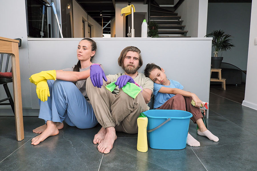 Tired Parents and Daughter Sit on Floor after Spring Cleaning