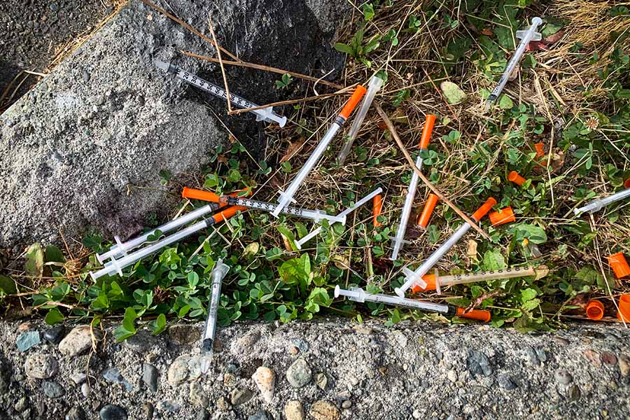 A group of discarded hypodermic needles laying on the ground