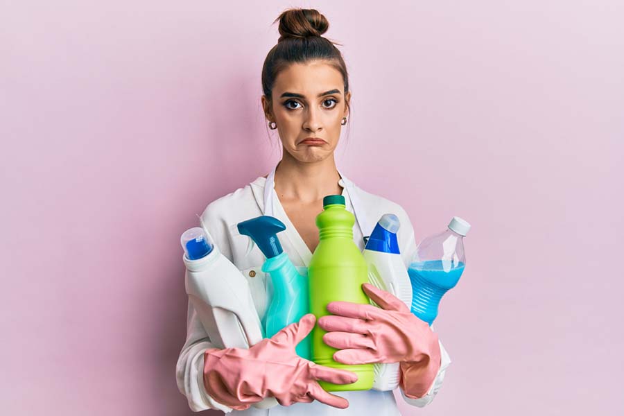 Woman holding cleaning products with a confused look on her face