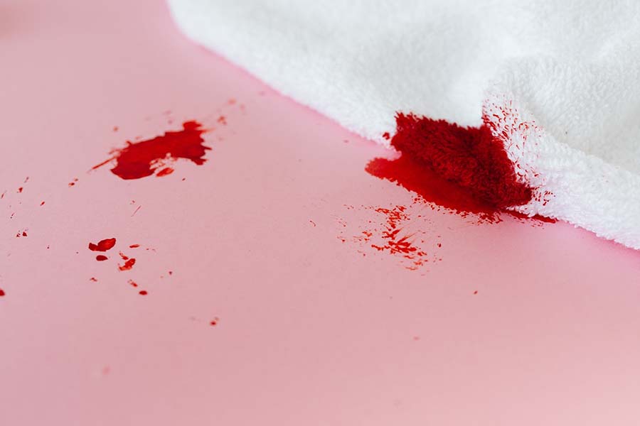 A blood stained towel lays on a pink background