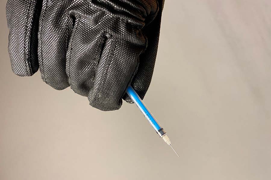 A Hexarmour needle resistance glove safely grasping a hypodermic needle