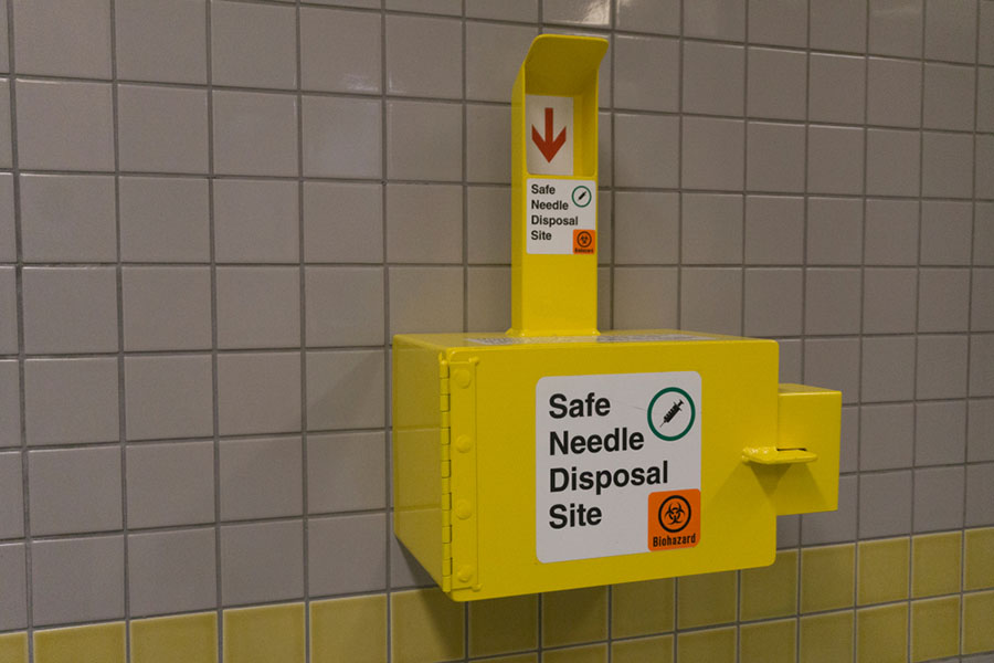 A sharps disposal box securely attached to a wall